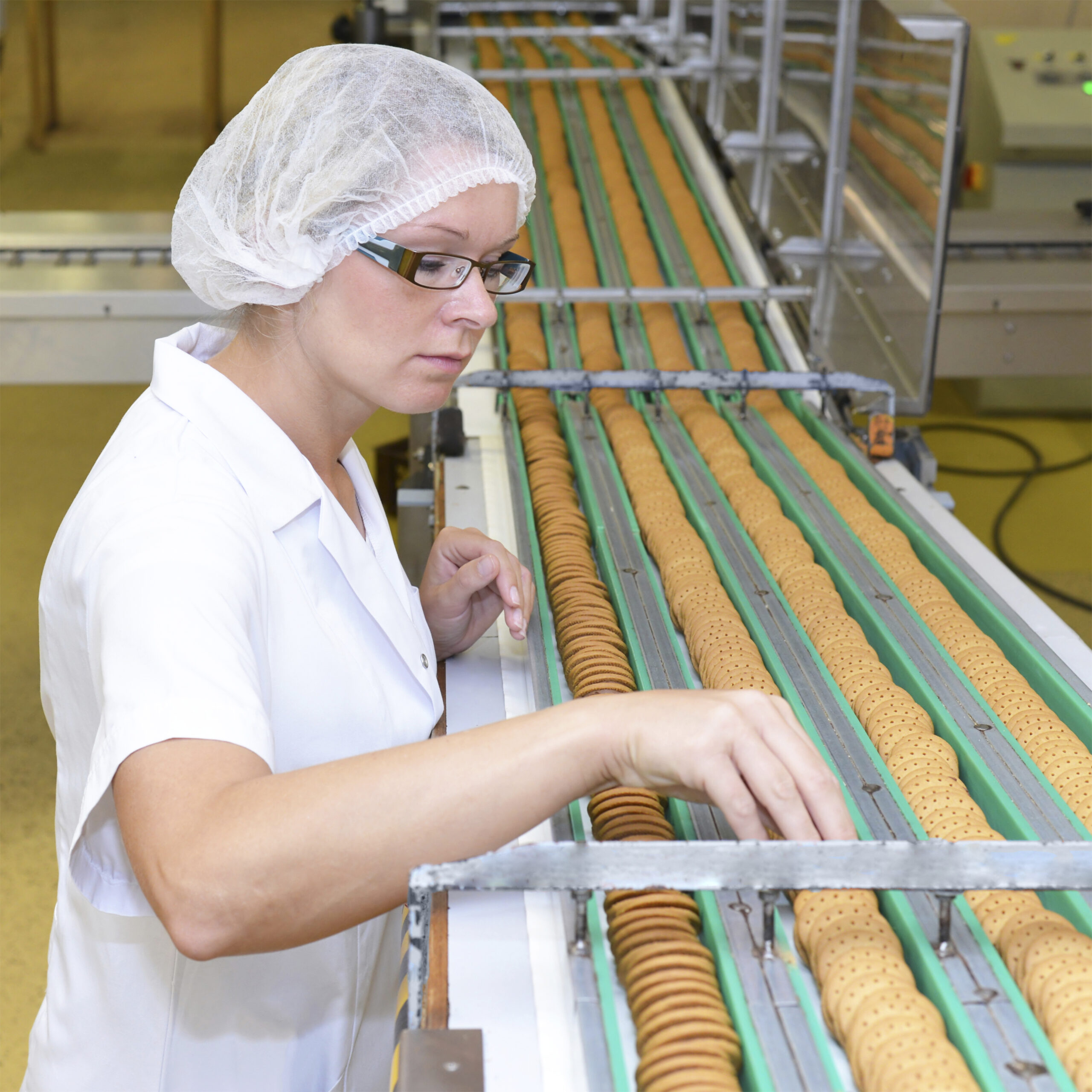 Germany, Saxony-Anhalt, woman controlling cookies on production line in a baking factory